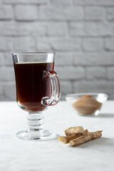 Healthy hot chicory drink in the glass cup , crushed chicory root in small glass bowl and chicory roots on concrete background. Side view
