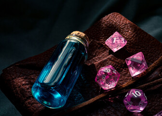 Close-up image of pink rpg dice and a glass stopper bottle on top of a leather-bound book