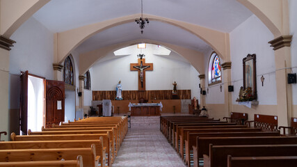 interior de iglesia rural con cristo crucificado al fondo y virgen y santo a los costados