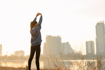 Woman is stretching her arms before workout outdoors in the city. Healthy young woman warming up outdoors in the morning.