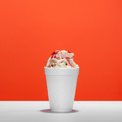 Mexican snack, trolley, prepared esquite, corn in a cup, with chili powder on orange background