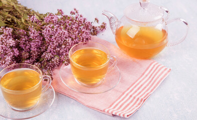Two cups and a teapot with tea with oregano. The concept of natural herbal tea