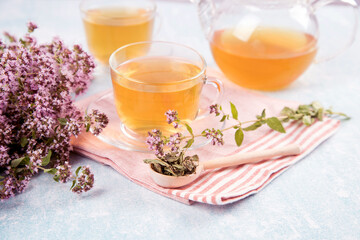 A wooden spoon and cups of tea with oregano.The concept of healthy natural herbal teas