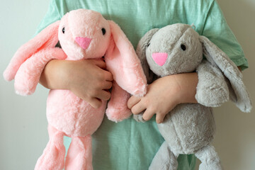Child holding plush bunny toys.