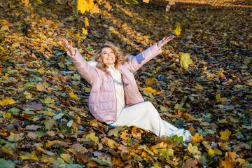 beautiful girl with blond hair in padded jacket on autumn leaves background, fall