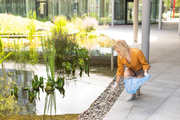 woman picking up plastic household waste in park