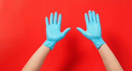 Two hand wearing blue latex gloves or surgical gloves on a red background.empty hand.