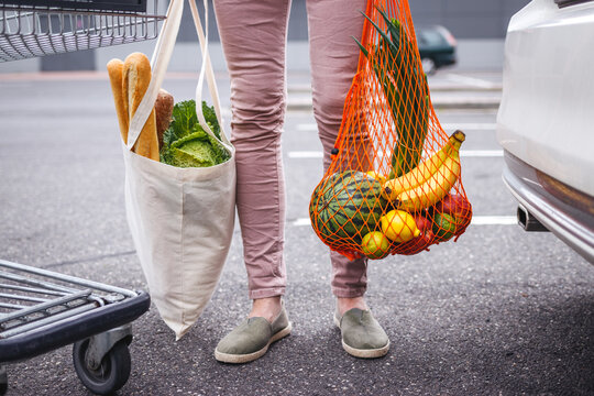 Reusable Textile Shopping Bag And Mesh Bag With Groceries Purchased. Woman Standing At Parking Lot After Shopping At Supermarket. Ethical Consumerism And Sustainable Lifestyle With Zero Waste