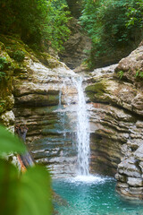 Waterfall landscape. Focus on waterfall, blurred leaves. Beautiful waterfall in tropical rainforest. Jungle river. Adventure in Asia. Cemara waterfall in Bali. Slow shutter speed, motion photography.