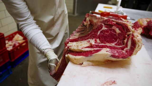 Butcher cuts up raw dry aged wagyu chuck beef ribs as close-up on a butchers table 