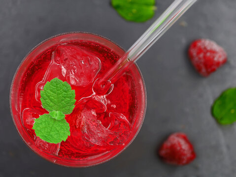 Top View Of Red Cocktail With Ice And Mint Leaf On Top On Black Stone Background