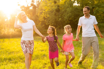 Fototapeta premium Mother and father with children running in green nature