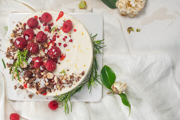 Cheesecake with raspberries, chocolate, hazelnuts and rosemary leaves on kitchen coutertop