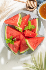 Composition of ripe watermelon and fresh mint on the kitchen table. Ripe summer watermelon. Juicy watermelon. Concept of seasonal fruits on the table