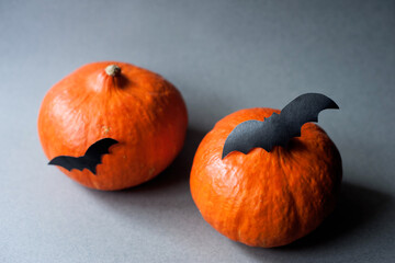 two pumpkins with a decor of paper bats on a gray background. Halloween Decor