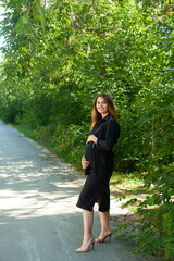 A beautiful stylish pregnant woman walks in the park. Fresh air, healthy lifestyle. Nature.