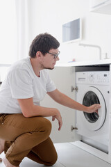 Young man putting clothes into washing machine