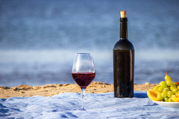 Picnic blanket, wine, fruit, beautiful sea beach. Selective focus