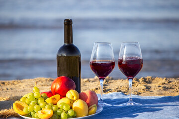 Obraz premium Picnic blanket, wine, fruit, beautiful sea beach. Selective focus