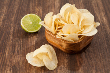Wooden Bowl With Tasty Potato Chips Lemon Flavor; Photo On Wooden Background