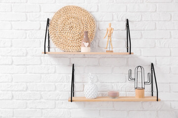 Modern shelves with decor hanging on brick wall