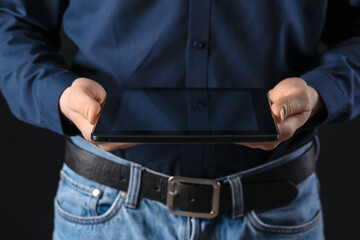 Young man with tablet computer on dark background