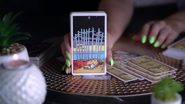Fortune teller woman showing the ten of swords , reading a future by tarot cards. Esoteric concept, fortune telling and predictions. Slow motion