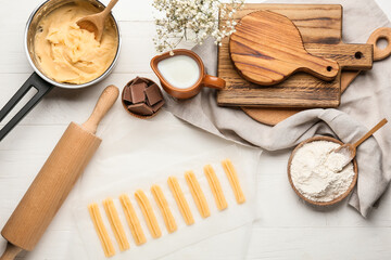 Uncooked churros and ingredients on light wooden background