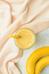 Glass of tasty banana daiquiri cocktail and fruits on grunge background