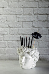 David's head plaster stand for office, creative and school supplies on a light background....