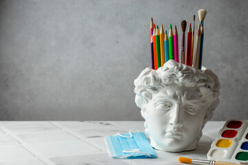 Fashionable concept. David's head plaster stand for office, creative and school supplies on a light...