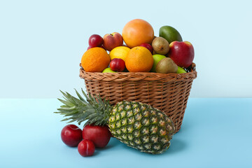 Basket with fresh fruits on color background