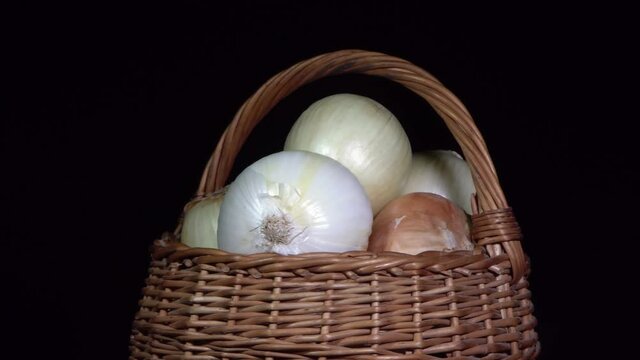 Vegetarian healthy food, composition of vegetables,  rotation of a basket with onions on a black background