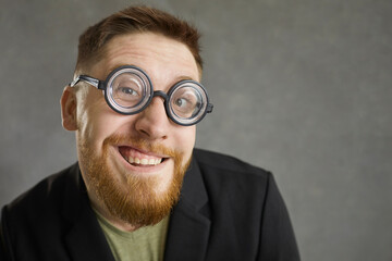 Funny curious man wearing retro vintage thick rimmed glasses smiling at camera. Studio closeup of...
