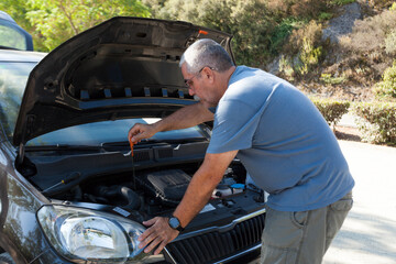 man senior looking at the oil level in the engine of the vehicle, heat hello, car breakdown, assistance, vehicle maintenance.