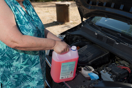 Woman Adding Car Coolant On The Road, Heat Wave, Car Breakdown, Vehicle Maintenance.