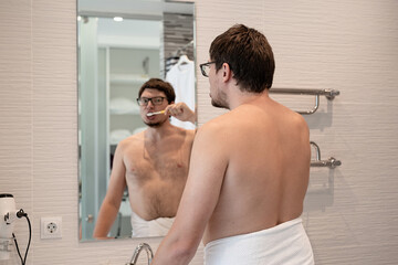 A young man brushing his teeth in the bathroom