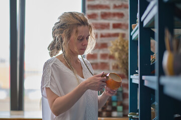 hostess of the ceramic workshop lays out her ceramic dishes on the shelves. feng shui concept....
