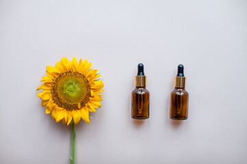 Flat lay of sunflowers and bottles for cosmetic serum or cream on a light pink background. The concept of beauty and preservation of youth. High quality photo