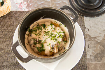 Potato pancake and mushroom sauce are in an old cast iron saucepan. Recipe of traditional Belarusian cuisine.