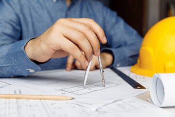Building concept. Civil male engineer working on blueprint architectural project at desk in office