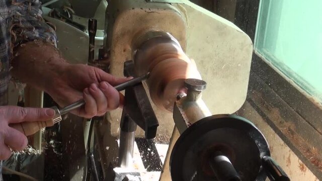 A turner cuts a piece of wood on a lathe