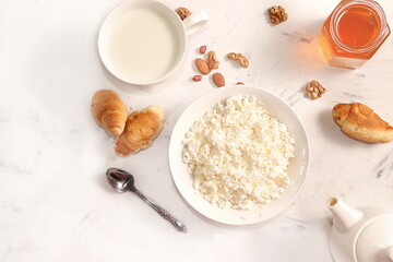 A healthy breakfast with ingredients, flat lay, fresh vog with milk and honey, croissants and nuts on a bright table. Healthy and natural food concept, lifestyle, top view,