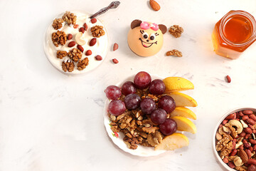 Healthy breakfast with ingredients, flat lay, fruit salad with muesli, apricots, grapes, honey and apple on a bright table. Healthy and natural food concept, lifestyle, top view,