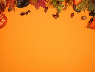 Flat lay still life photo on orange background for fall.  Top is decorated with acorns, autumn leaves, gourds,  pumpkins, leaves.  Lots of copy space