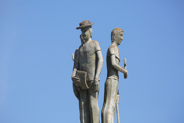 Statue on the side of a large and beautiful country road.
