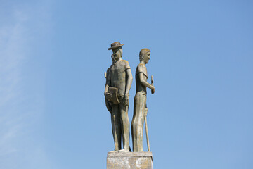 Statue on the side of a large and beautiful country road.
