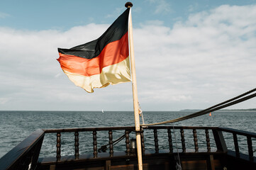 Wehende Deutschland Fahne, Flagge auf altem Schiff mit Reling. Himmel und Wasser im Hintergrund. Viel Platz für Text