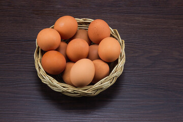 Eggs chicken in the basket on brown dark wooden floor.