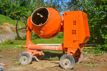 An orange cement mixer on a sunny building site.